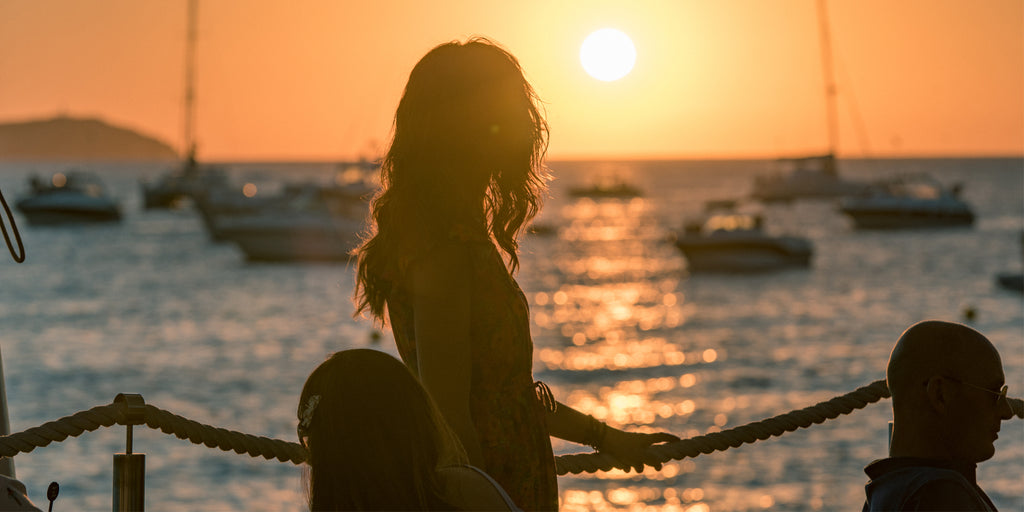 An image of a young woman standing by her table at Café del Mar watching the sunset